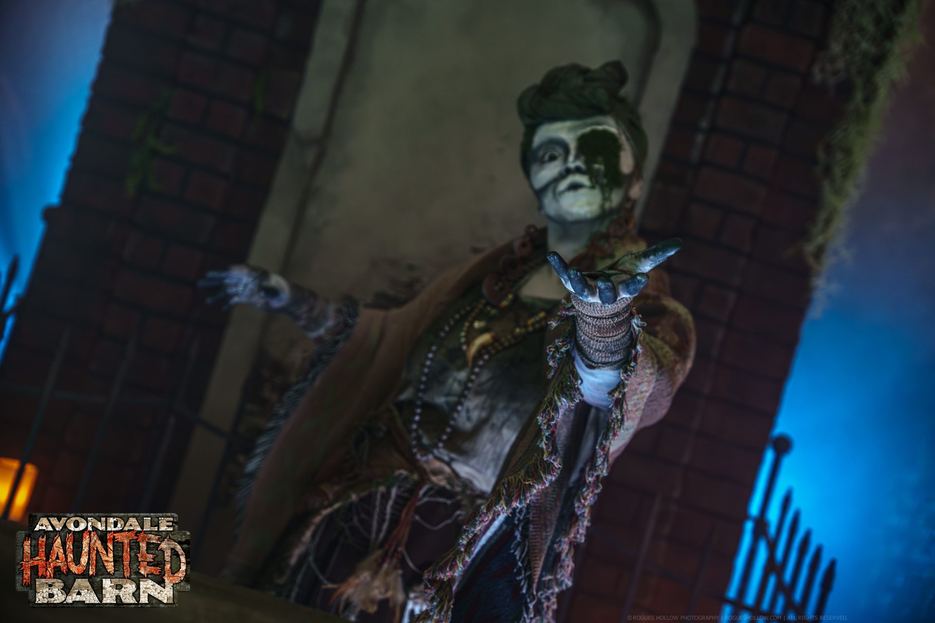 A costumed creature reaches toward guests inside Avondale Haunted Barn.