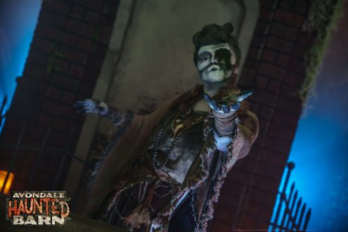 A costumed creature reaches toward guests inside Avondale Haunted Barn.