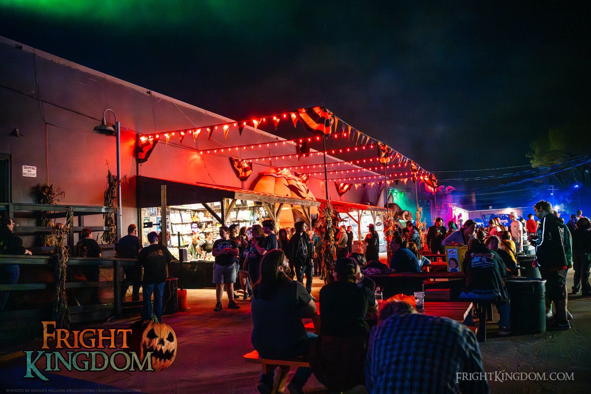 Guests gather beneath orange lights in the Fright Kingdom midway.